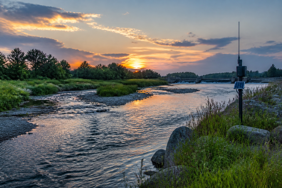 Flusslandschaft mit Umgehungsgewässer und Monitoringantenne in der Dämmerung